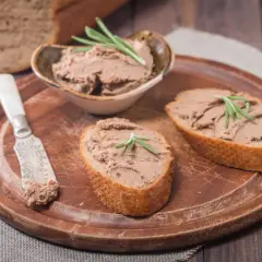 Pyszny pasztet z wątróbki na chrupiących kromkach chleba, udekorowany gałązką rozmarynu. Idealny na śniadanie lub przekąskę.