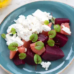 Kolorowa sałatka na kolację: buraki, grejpfrut i ser feta, udekorowana zielonymi listkami.