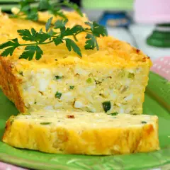 Pyszny pasztet z jajek, z kawałkami jajek i szczypiorku, udekorowany natką pietruszki, podany na zielonym talerzu.