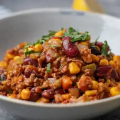 A miseczce znajduje się aromatyczne chili con carne z fasolą, kukurydzą i mielonym mięsem, posypane świeżą natką pietruszki.