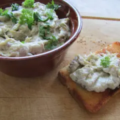 Pyszna pasta z bakłażana, kremowa i aromatyczna, podana w miseczce i na grzance, ozdobiona natką pietruszki.