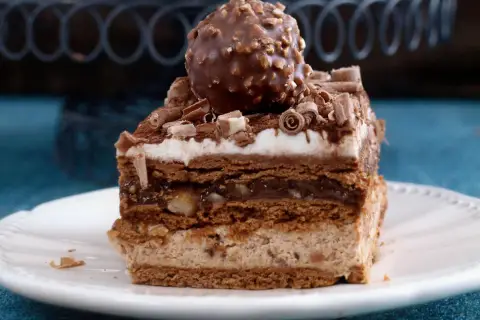 Pyszne ciasto Ferrero Rocher z warstwami czekolady, kremu i orzechów, zwieńczone całą czekoladką.