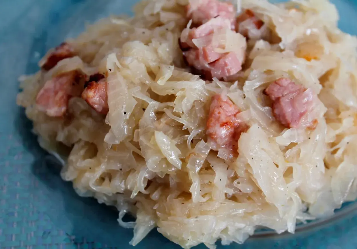 Pyszna kapusta zasmażana z boczkiem, podana na talerzu. Aromatyczne danie, które rozpływa się w ustach.